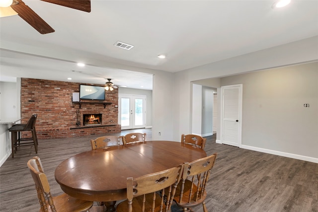 dining area with french doors, ceiling fan, dark hardwood / wood-style floors, a brick fireplace, and brick wall