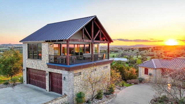 exterior space featuring a standing seam roof, metal roof, a balcony, a garage, and stone siding