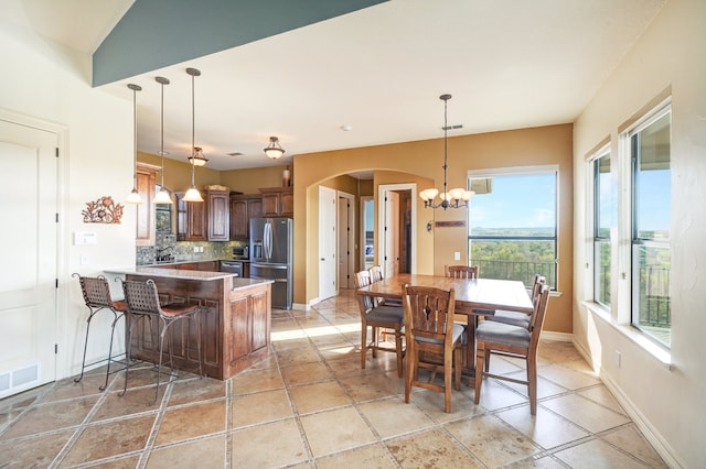 kitchen with decorative light fixtures, kitchen peninsula, stainless steel appliances, and tasteful backsplash