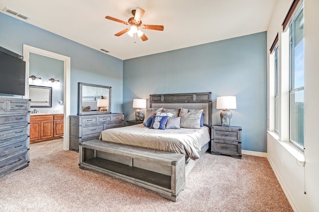 bedroom with ceiling fan, connected bathroom, and light carpet