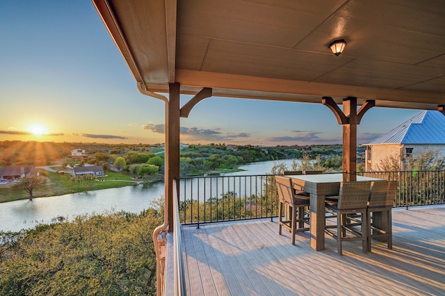 deck at dusk featuring a water view