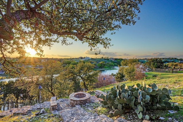 yard at dusk featuring a water view and a fire pit