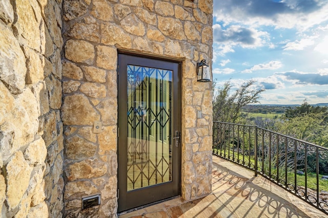 doorway to property featuring stone siding and a balcony