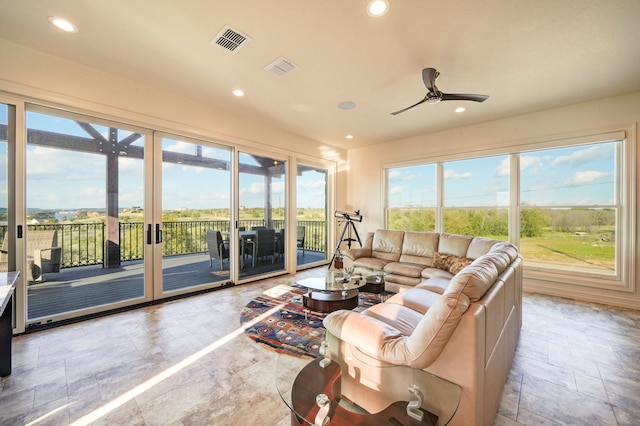 living room featuring stone finish floor, ceiling fan, visible vents, and recessed lighting