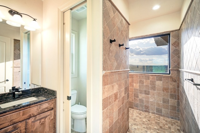 full bath with visible vents, tiled shower, vanity, and toilet