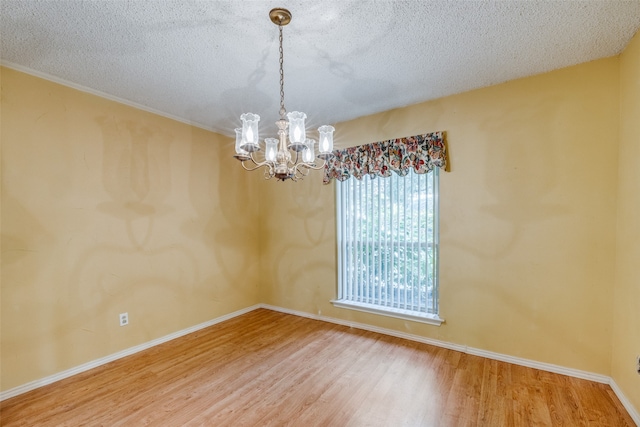 spare room featuring a notable chandelier, a textured ceiling, and hardwood / wood-style flooring