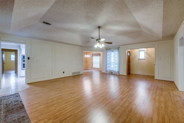 empty room with ceiling fan, a textured ceiling, and light hardwood / wood-style flooring