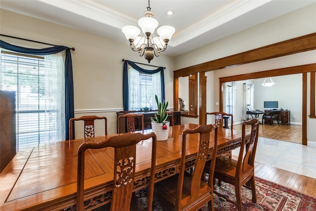 dining room featuring a tray ceiling, hardwood / wood-style flooring, a healthy amount of sunlight, and an inviting chandelier