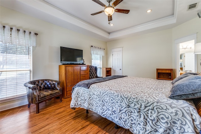 bedroom with a raised ceiling, ceiling fan, and wood-type flooring