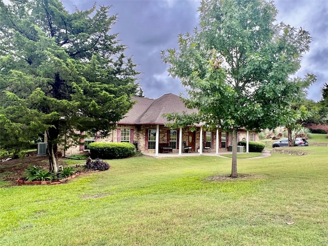 view of front of property with a front yard and central AC