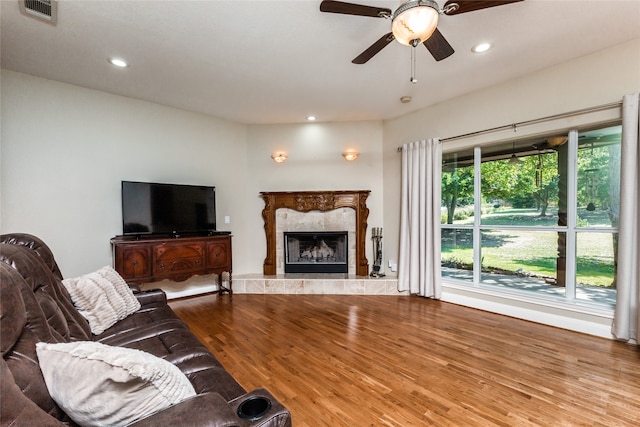 living room featuring hardwood / wood-style floors, ceiling fan, and a premium fireplace