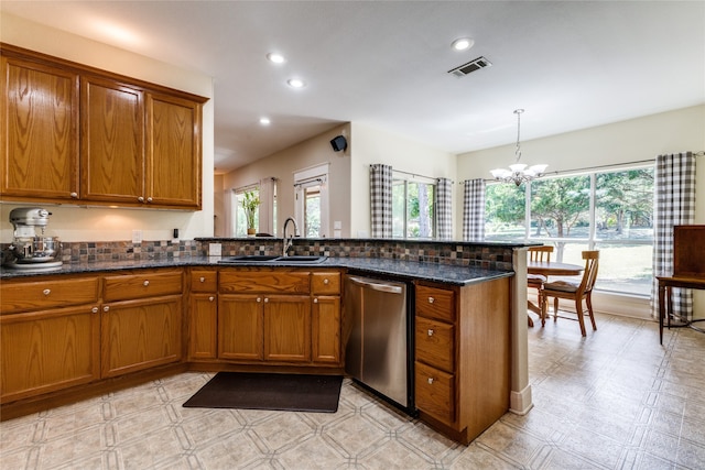 kitchen featuring pendant lighting, sink, stainless steel dishwasher, dark stone countertops, and a notable chandelier