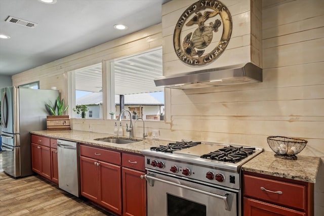 1320 Murrah Ln, Kaufman, TX 75142 - kitchen with stainless steel appliances, light wood finished floors, wall chimney range hood, light stone counters, and dark brown cabinets
