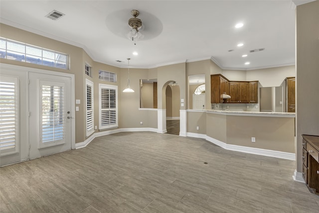 unfurnished living room with light wood-type flooring, ceiling fan, and ornamental molding