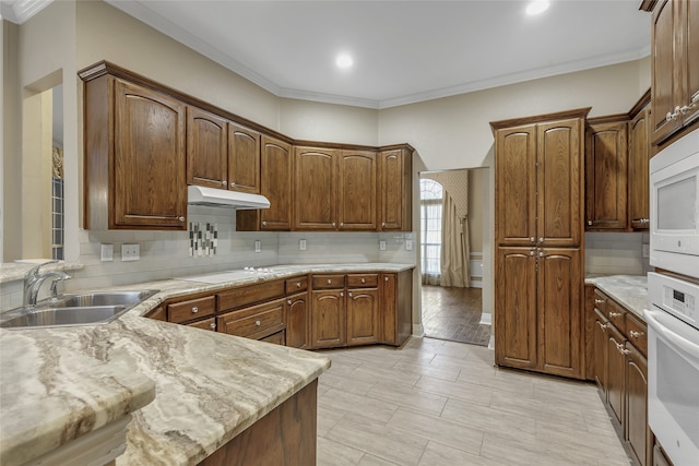 kitchen with crown molding, white appliances, tasteful backsplash, sink, and light stone countertops