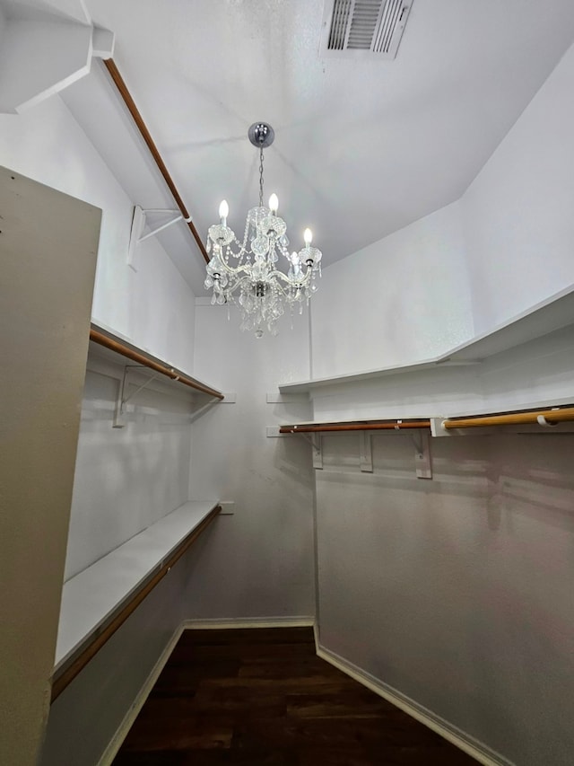 walk in closet featuring dark hardwood / wood-style flooring, a notable chandelier, and vaulted ceiling