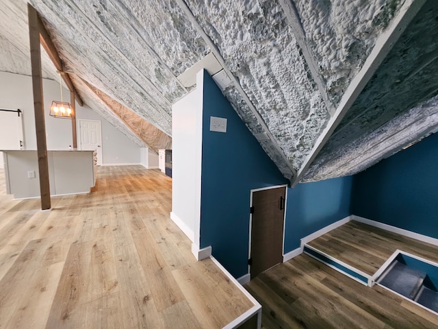 additional living space featuring lofted ceiling, light hardwood / wood-style flooring, and a notable chandelier