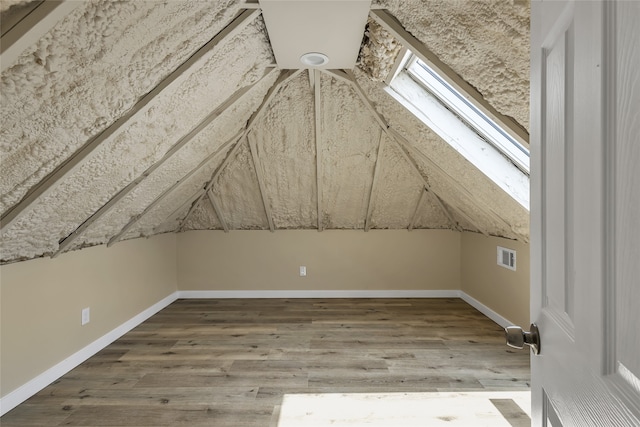 additional living space featuring vaulted ceiling with skylight and wood-type flooring