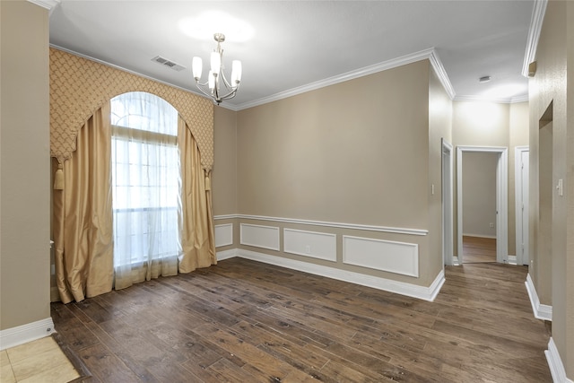 spare room with crown molding, dark wood-type flooring, and a chandelier