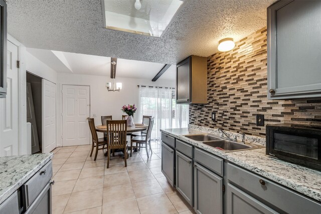 kitchen featuring decorative light fixtures, decorative backsplash, sink, a textured ceiling, and gray cabinetry