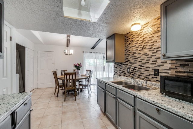 kitchen with decorative light fixtures, sink, decorative backsplash, light tile patterned floors, and a textured ceiling