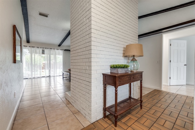 hallway with a textured ceiling, tile patterned floors, and beam ceiling