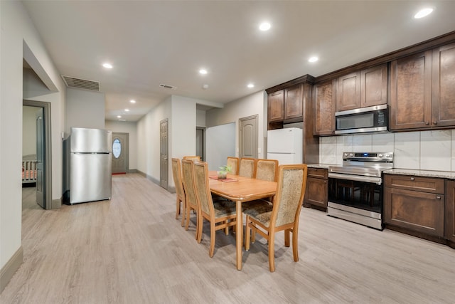 kitchen with dark brown cabinetry, tasteful backsplash, stainless steel appliances, and light hardwood / wood-style floors