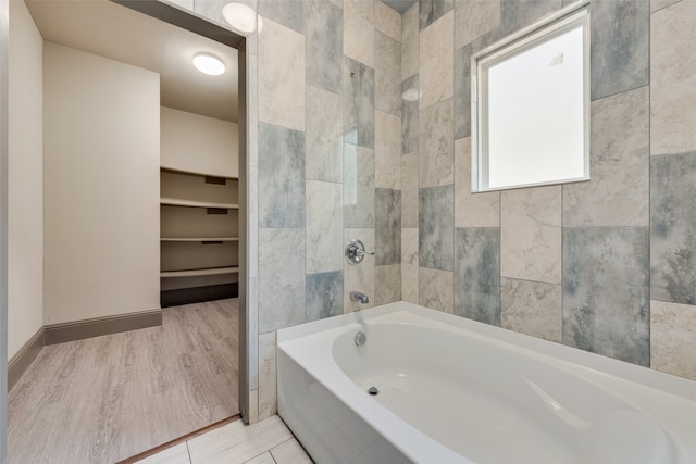 bathroom with tile walls, a washtub, and hardwood / wood-style floors