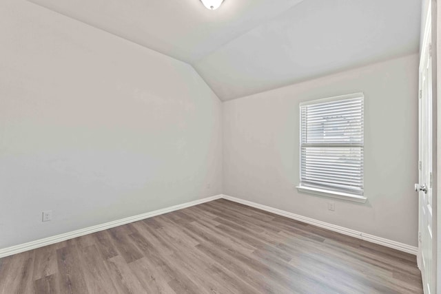 spare room featuring hardwood / wood-style flooring and vaulted ceiling