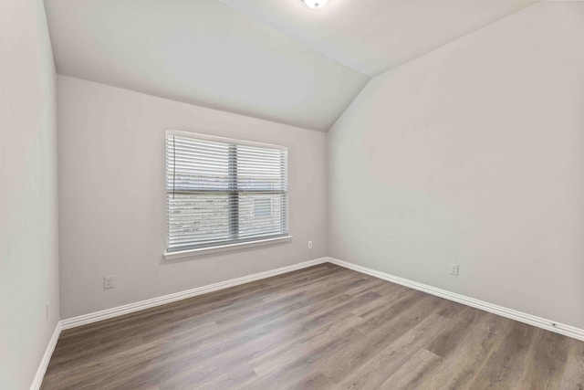 empty room featuring hardwood / wood-style flooring and vaulted ceiling