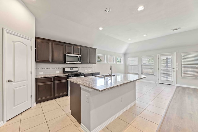 kitchen with lofted ceiling, appliances with stainless steel finishes, sink, decorative backsplash, and a center island with sink