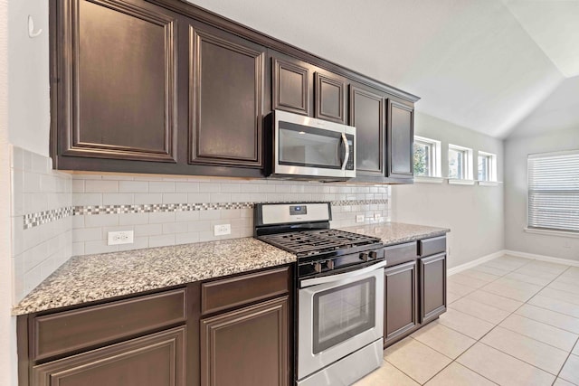 kitchen featuring light tile patterned flooring, tasteful backsplash, dark brown cabinetry, appliances with stainless steel finishes, and lofted ceiling