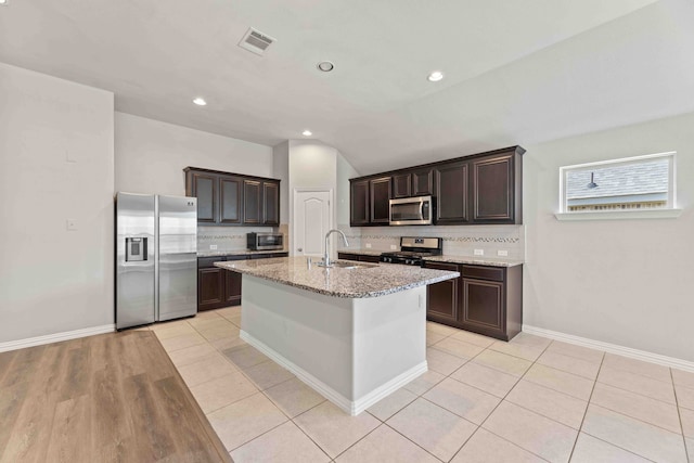 kitchen with light hardwood / wood-style flooring, tasteful backsplash, appliances with stainless steel finishes, sink, and a center island with sink