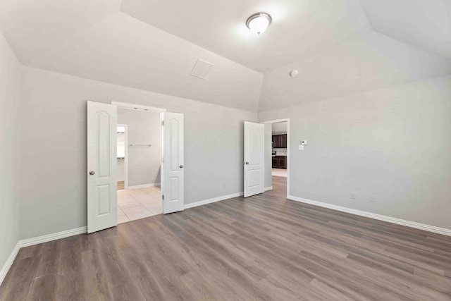 unfurnished bedroom with hardwood / wood-style flooring and lofted ceiling