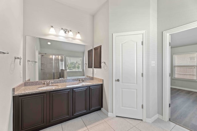 bathroom with a shower with door, double vanity, and tile patterned floors