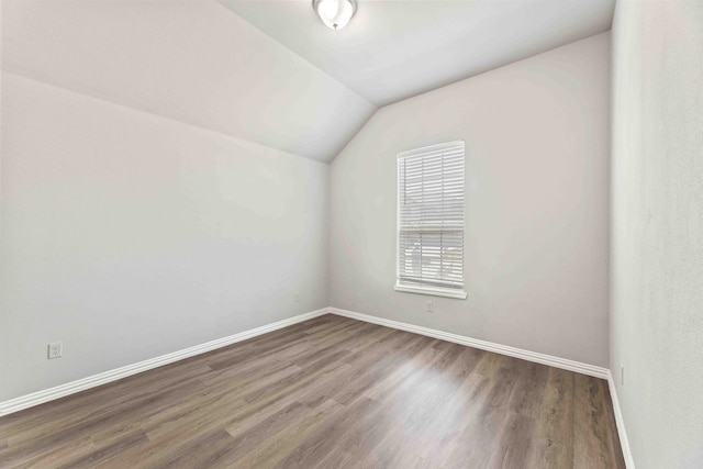 spare room with wood-type flooring and lofted ceiling