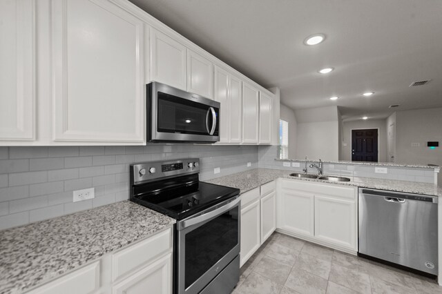 kitchen with tasteful backsplash, stainless steel appliances, sink, light tile patterned floors, and white cabinetry