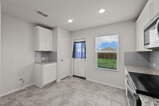 kitchen featuring white cabinets, light tile patterned floors, decorative backsplash, and stainless steel appliances