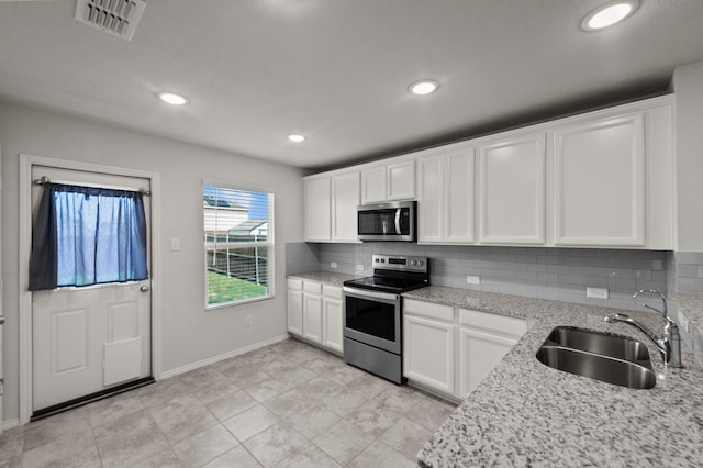 kitchen featuring stainless steel appliances, sink, light stone counters, backsplash, and light tile patterned floors