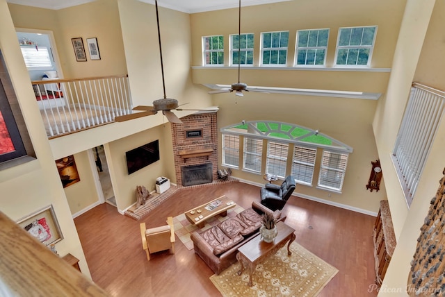 living room featuring crown molding, ceiling fan, wood-type flooring, and a towering ceiling