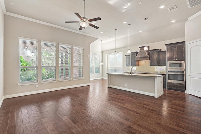 kitchen with ceiling fan, hanging light fixtures, decorative backsplash, a center island with sink, and appliances with stainless steel finishes