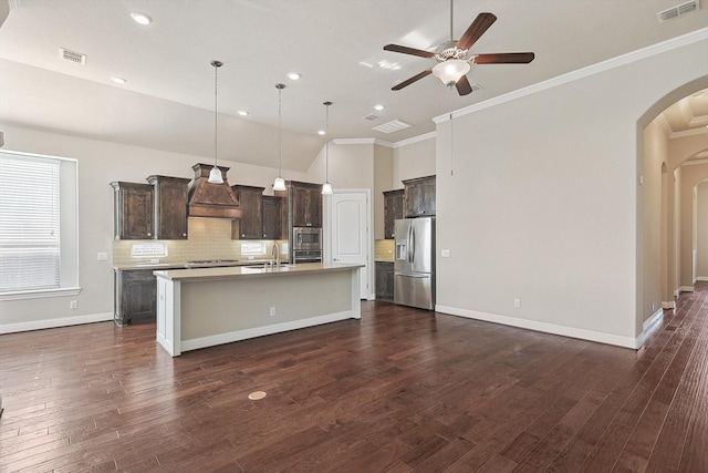 kitchen with pendant lighting, backsplash, a center island with sink, sink, and stainless steel appliances