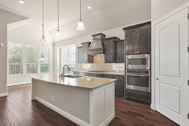 kitchen featuring pendant lighting, a center island with sink, sink, vaulted ceiling, and stainless steel appliances