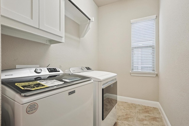 laundry room with cabinets, washing machine and dryer, and light tile patterned flooring