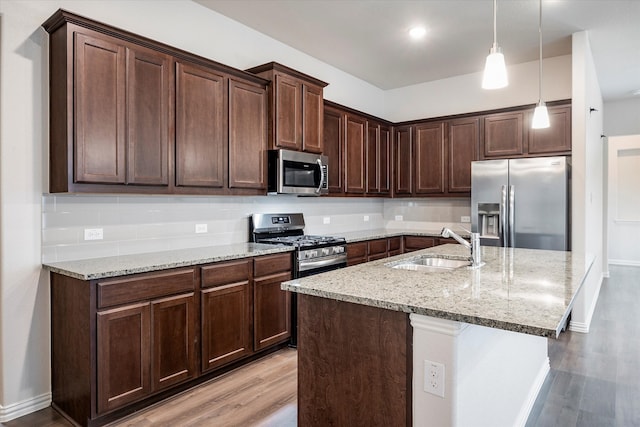 kitchen with stainless steel appliances, light hardwood / wood-style floors, decorative backsplash, dark brown cabinetry, and sink