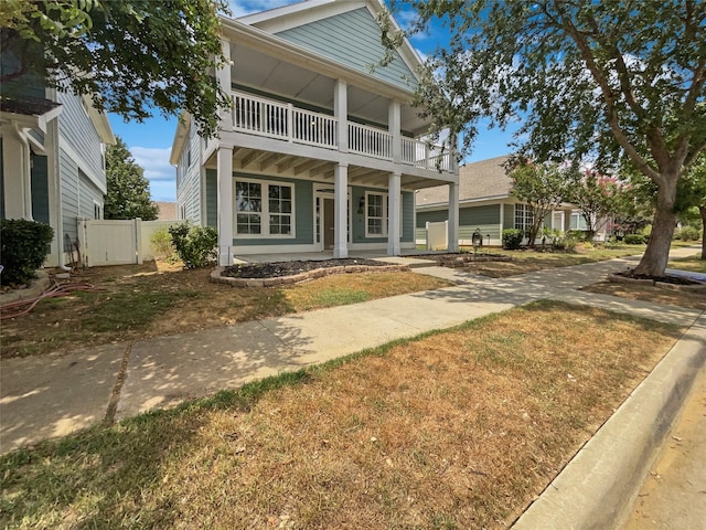 view of front facade featuring a balcony, covered porch, and a front lawn