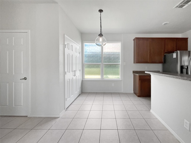 kitchen featuring light tile patterned flooring, pendant lighting, and stainless steel fridge