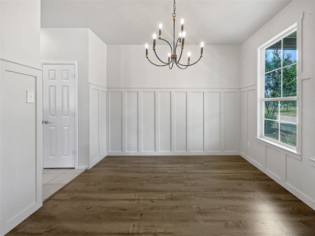 unfurnished dining area featuring hardwood / wood-style flooring, plenty of natural light, and a chandelier