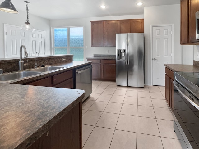 kitchen with appliances with stainless steel finishes, light tile patterned flooring, pendant lighting, and sink