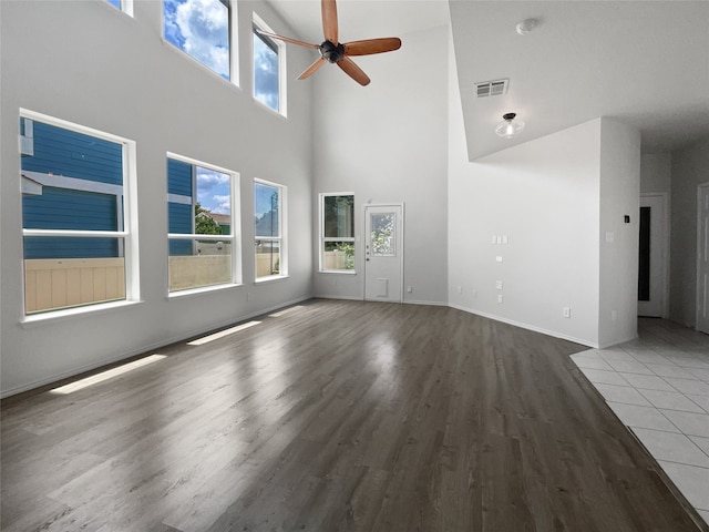 unfurnished living room with a high ceiling, ceiling fan, and light hardwood / wood-style floors